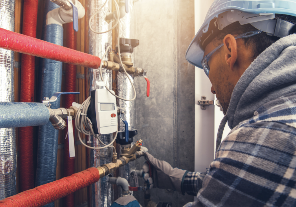 photo of technical using a meter to look at heating system with red and blue pipes