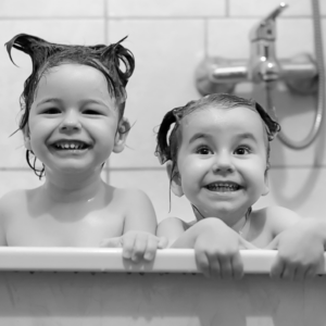 Black and white photo of two young children in the bathtub