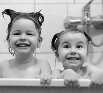 Black and white photo of two young children in the bathtub