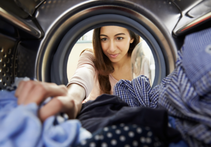 Photo taken from inside dryer of a woman reaching into dryer to get clothes out